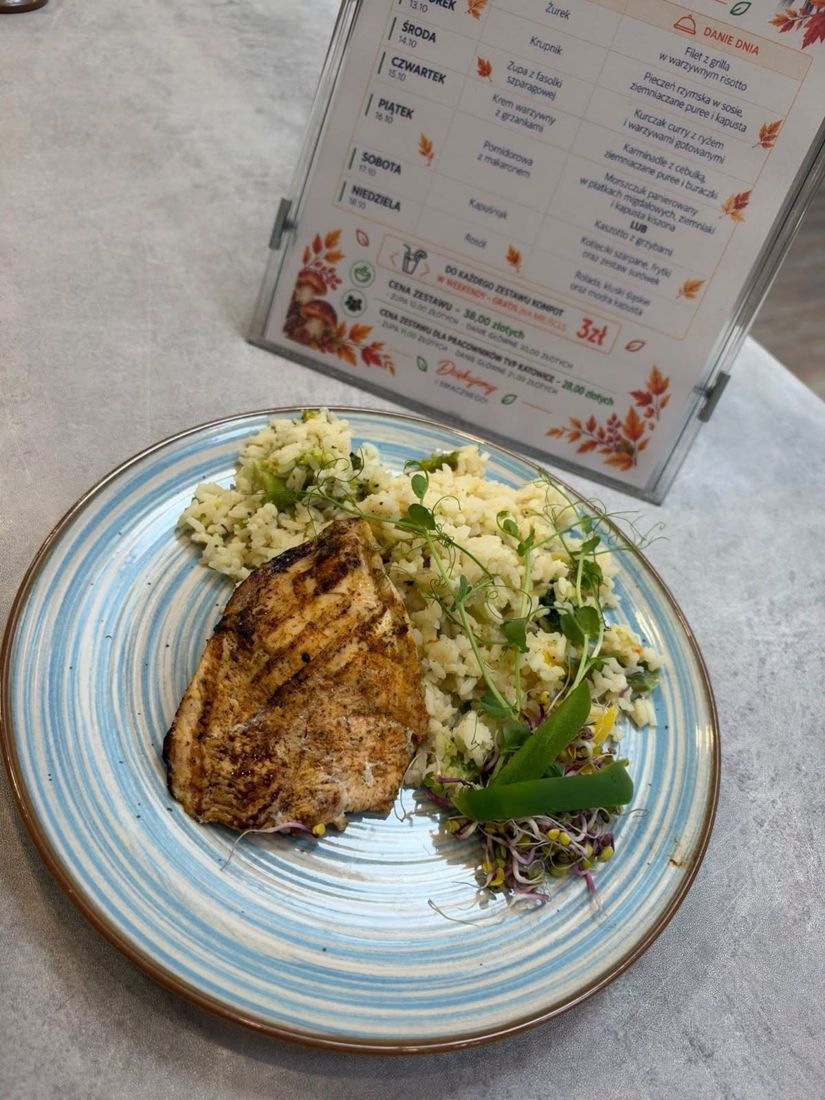 Filet z grilla w warzywnym risotto, w tle karta z menu tygodnia